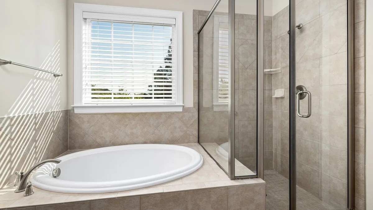 Tile setter finishing shower walls in a Newark, NJ bathroom